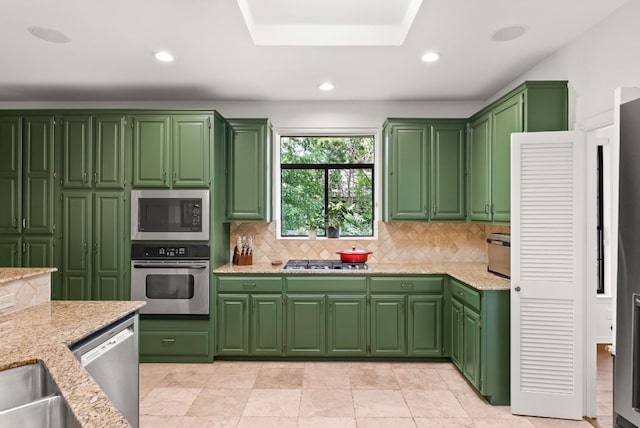 kitchen with light stone counters, recessed lighting, backsplash, and stainless steel appliances
