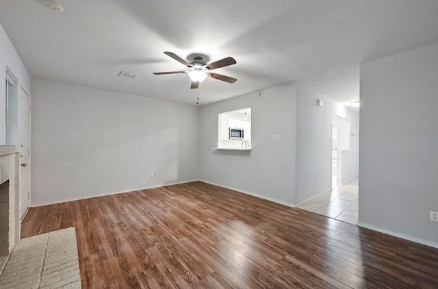 1815 River Crossing Cir Unit A, Austin, TX 78741 - unfurnished living room featuring a ceiling fan, wood finished floors, a fireplace, and baseboards