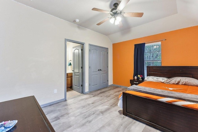 bedroom featuring baseboards, ensuite bathroom, light wood-style flooring, and lofted ceiling