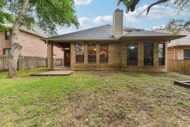back of property featuring brick siding, a fenced backyard, a chimney, a patio area, and a lawn