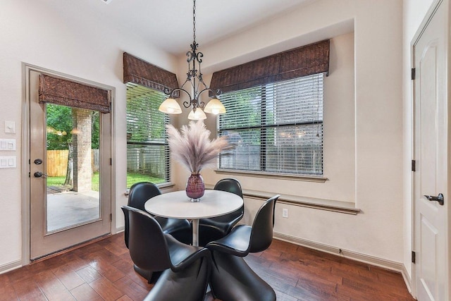 dining area featuring dark wood-style flooring, baseboards, and a notable chandelier