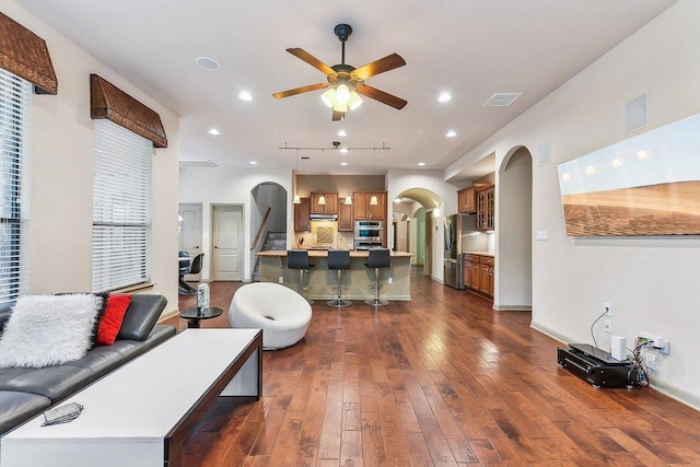 living room featuring ceiling fan, arched walkways, dark wood finished floors, recessed lighting, and visible vents