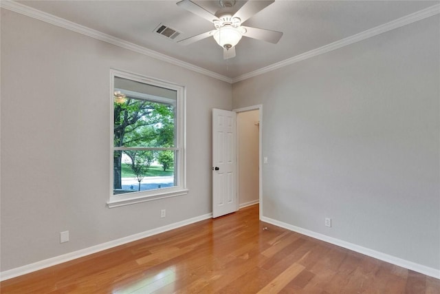 empty room featuring visible vents, crown molding, wood finished floors, baseboards, and a ceiling fan
