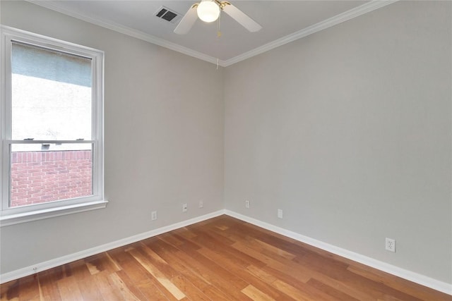 unfurnished room with wood-type flooring, ornamental molding, visible vents, baseboards, and a ceiling fan
