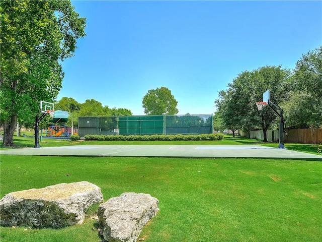 view of community with a lawn, community basketball court, and fence