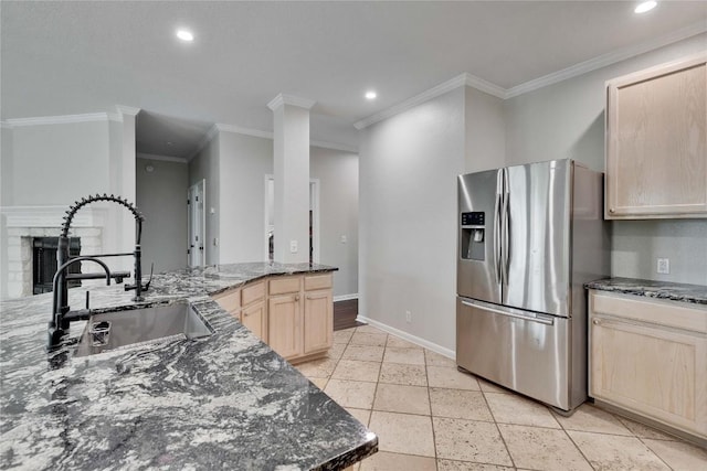 kitchen with a sink, light brown cabinets, recessed lighting, baseboards, and stainless steel refrigerator with ice dispenser