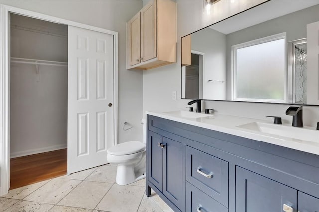bathroom with double vanity, a sink, an enclosed shower, and toilet