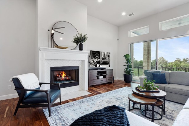 living area with visible vents, baseboards, a high ceiling, and wood finished floors