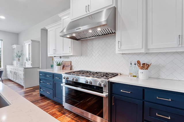 kitchen with high end range, blue cabinetry, under cabinet range hood, and dark wood finished floors
