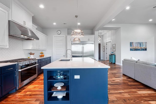 504 Loyal June Trl, Leander, TX 78641 - kitchen featuring under cabinet range hood, premium appliances, blue cabinets, wood finished floors, and recessed lighting