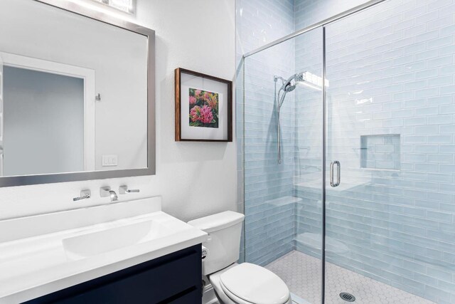 full bathroom with vanity, a stall shower, and toilet
