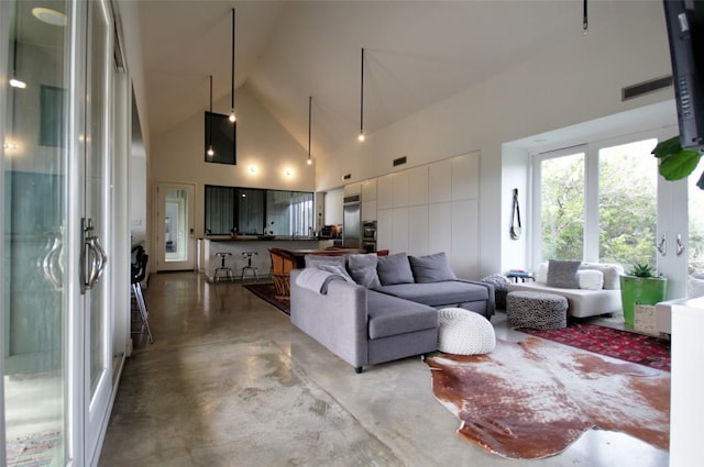 living room featuring high vaulted ceiling and concrete floors