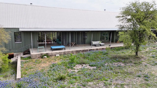 rear view of house featuring board and batten siding, a patio area, and metal roof