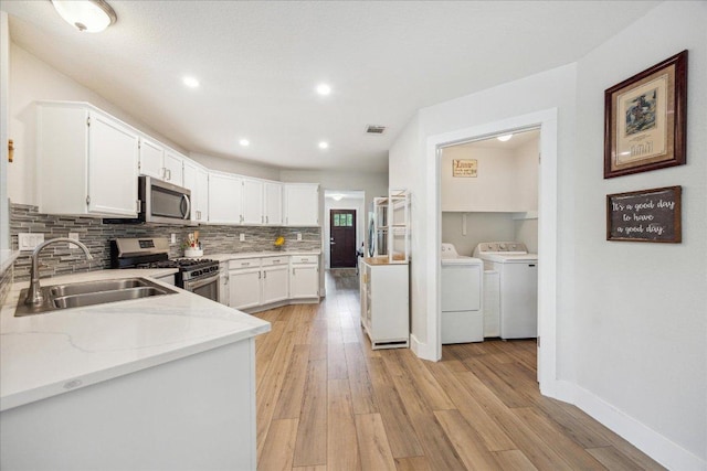 kitchen with backsplash, visible vents, a sink, separate washer and dryer, and stainless steel appliances