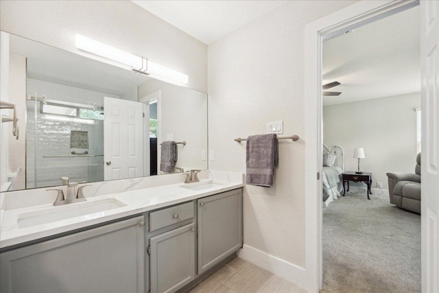 ensuite bathroom with double vanity, baseboards, a sink, and a stall shower