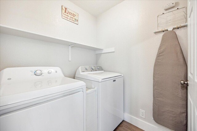 laundry area with baseboards, laundry area, independent washer and dryer, and wood finished floors