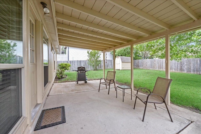 view of patio with a storage shed, an outbuilding, a fenced backyard, and grilling area