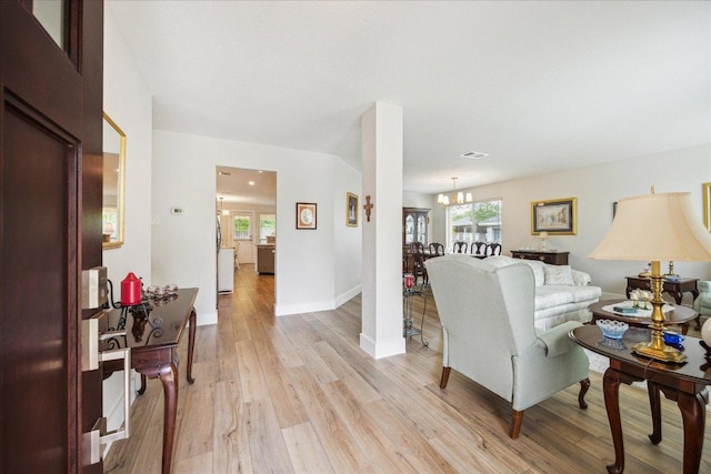 living room featuring light wood-style floors, baseboards, a notable chandelier, and visible vents