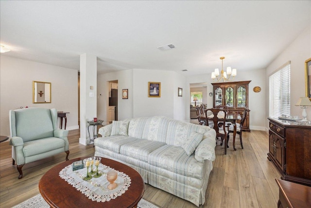 living room with a chandelier, visible vents, and light wood-style flooring