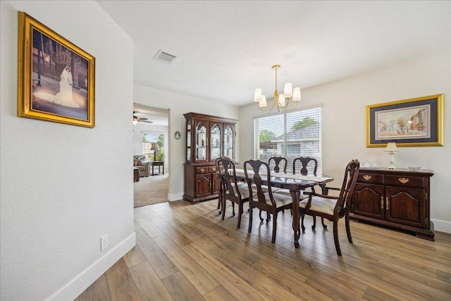 dining area with a healthy amount of sunlight, visible vents, light wood-type flooring, and a chandelier