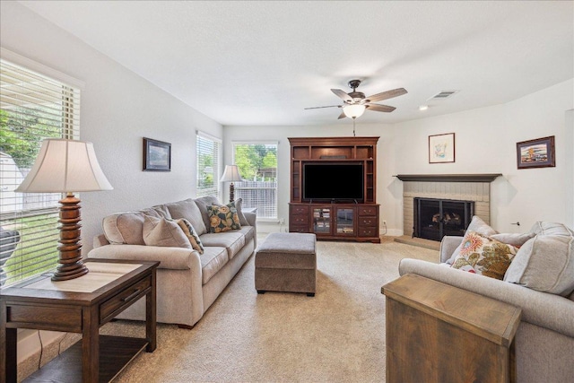 living area featuring a ceiling fan, visible vents, light carpet, and a fireplace