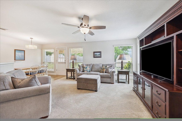 living area featuring visible vents, a ceiling fan, and light colored carpet
