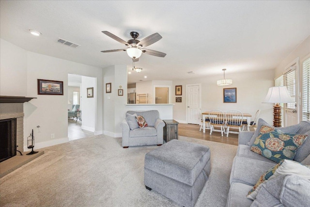 living room with a ceiling fan, visible vents, a brick fireplace, baseboards, and recessed lighting