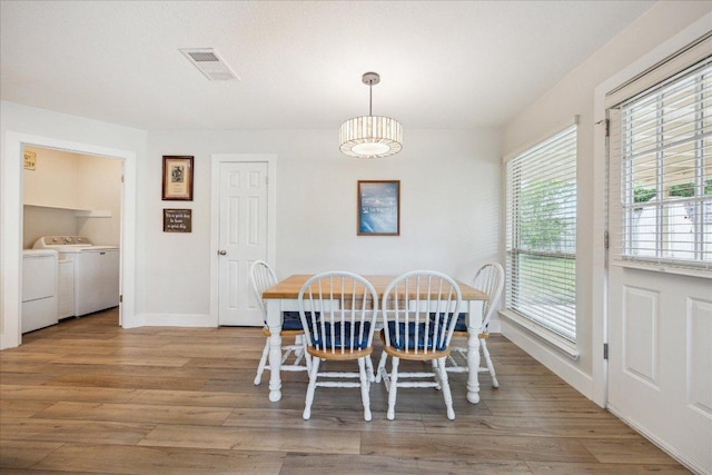dining room with visible vents, baseboards, wood finished floors, and washing machine and clothes dryer