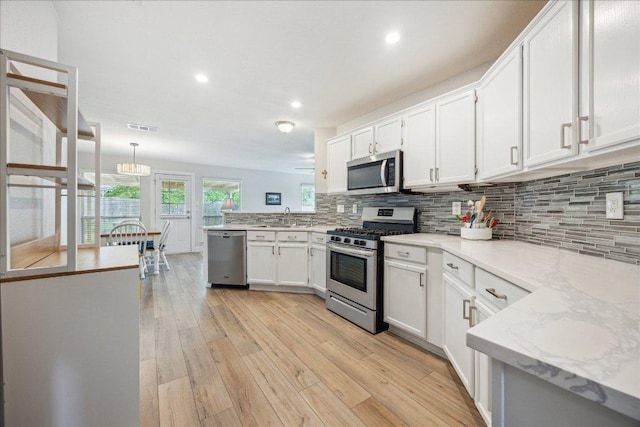kitchen featuring visible vents, tasteful backsplash, a sink, stainless steel appliances, and light wood-style flooring