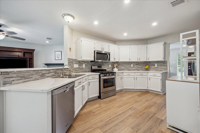 kitchen featuring visible vents, appliances with stainless steel finishes, light wood-type flooring, a sink, and a peninsula