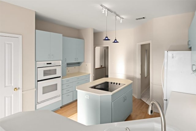 kitchen featuring a kitchen island, visible vents, light countertops, white appliances, and light wood-style flooring