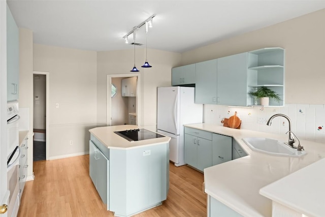 kitchen featuring a sink, black electric cooktop, light wood-style flooring, a center island, and freestanding refrigerator