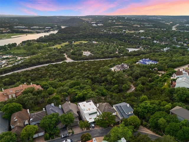 aerial view at dusk with a water view and a residential view