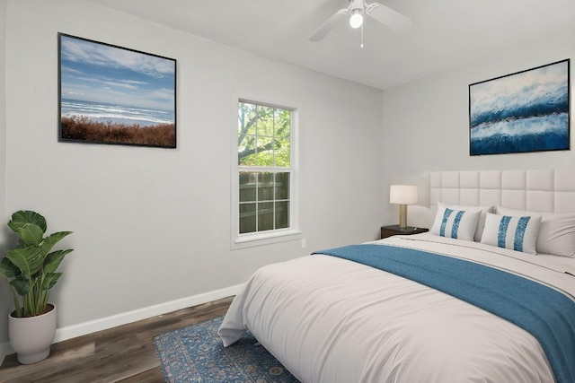 bedroom with baseboards, a ceiling fan, a water view, and wood finished floors