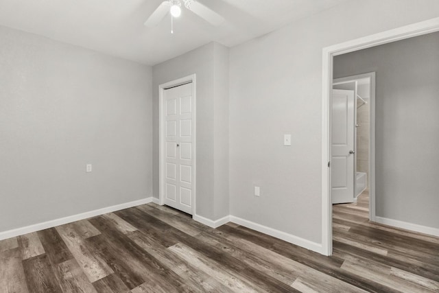 unfurnished bedroom featuring baseboards, a ceiling fan, dark wood-style floors, and a closet