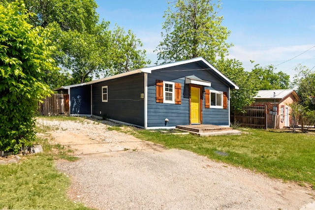 view of front of house with fence, an outdoor structure, and a front yard