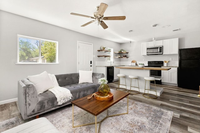 living area with visible vents, dark wood-type flooring, baseboards, and ceiling fan
