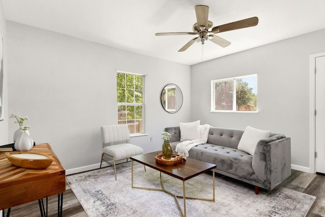 living area with baseboards, ceiling fan, and wood finished floors