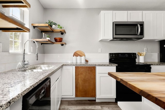 kitchen featuring wooden counters, open shelves, a sink, black appliances, and white cabinetry
