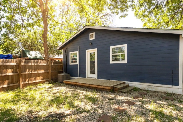 rear view of property featuring a deck and fence