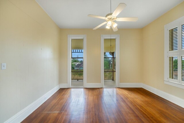 unfurnished room featuring baseboards, a ceiling fan, wood finished floors, and a healthy amount of sunlight