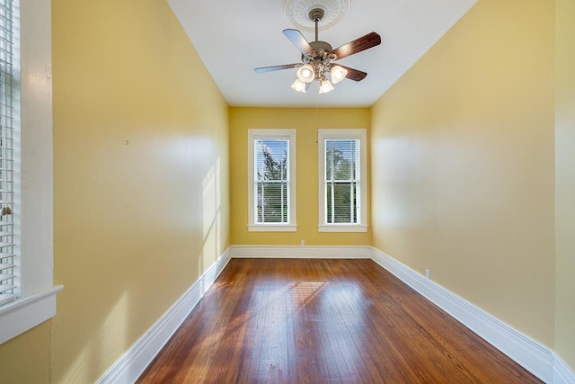 unfurnished room featuring wood-type flooring, a ceiling fan, and baseboards