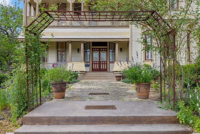 view of exterior entry with a porch and a balcony
