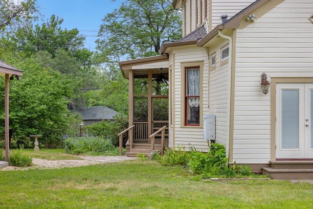 view of exterior entry featuring a yard and a shingled roof