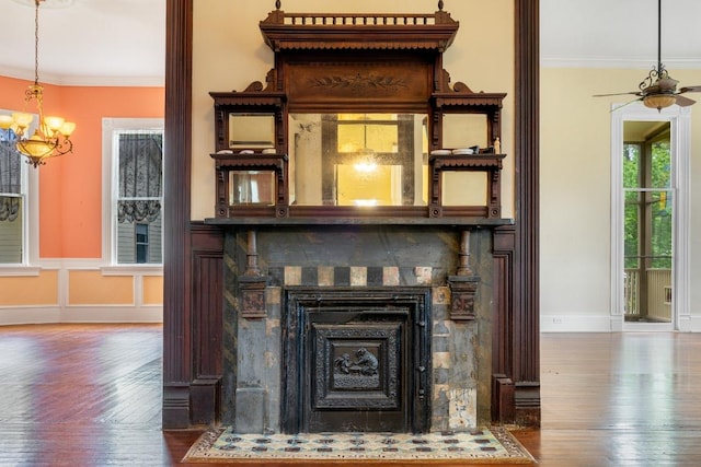 room details featuring crown molding, a chandelier, baseboards, a fireplace with flush hearth, and wood finished floors