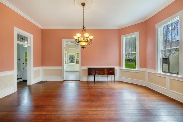 dining area featuring an inviting chandelier, a wainscoted wall, crown molding, and hardwood / wood-style floors