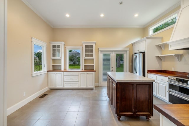 kitchen with appliances with stainless steel finishes, ornamental molding, open shelves, and french doors
