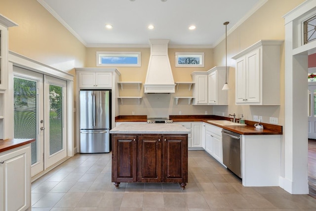 kitchen with crown molding, open shelves, a sink, premium range hood, and stainless steel appliances