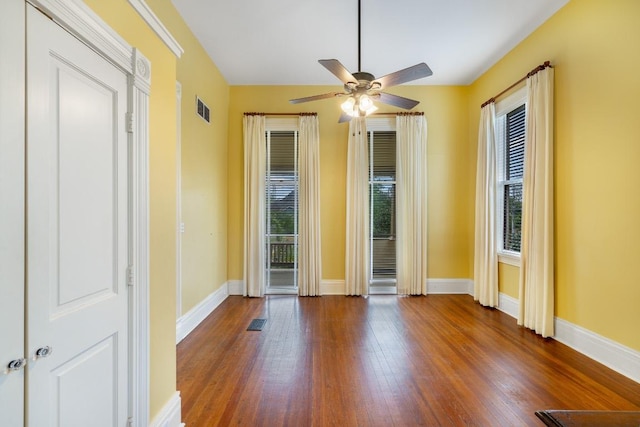 unfurnished room featuring visible vents, ceiling fan, wood finished floors, and a healthy amount of sunlight
