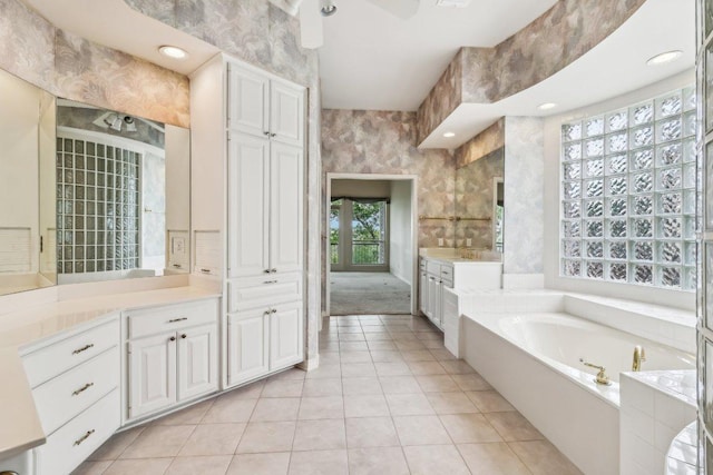 bathroom featuring tile patterned floors, wallpapered walls, a garden tub, and vanity